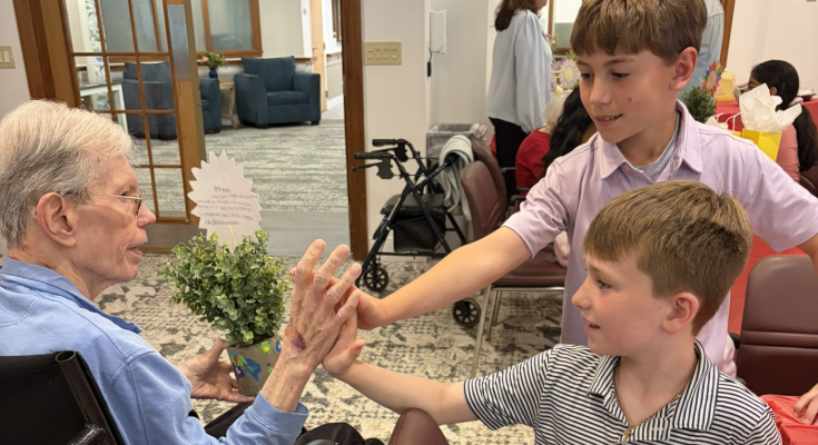 A male resident high-fives two male Exton Elementary School students during the “Voices of the Past, Stories for the Future” program.