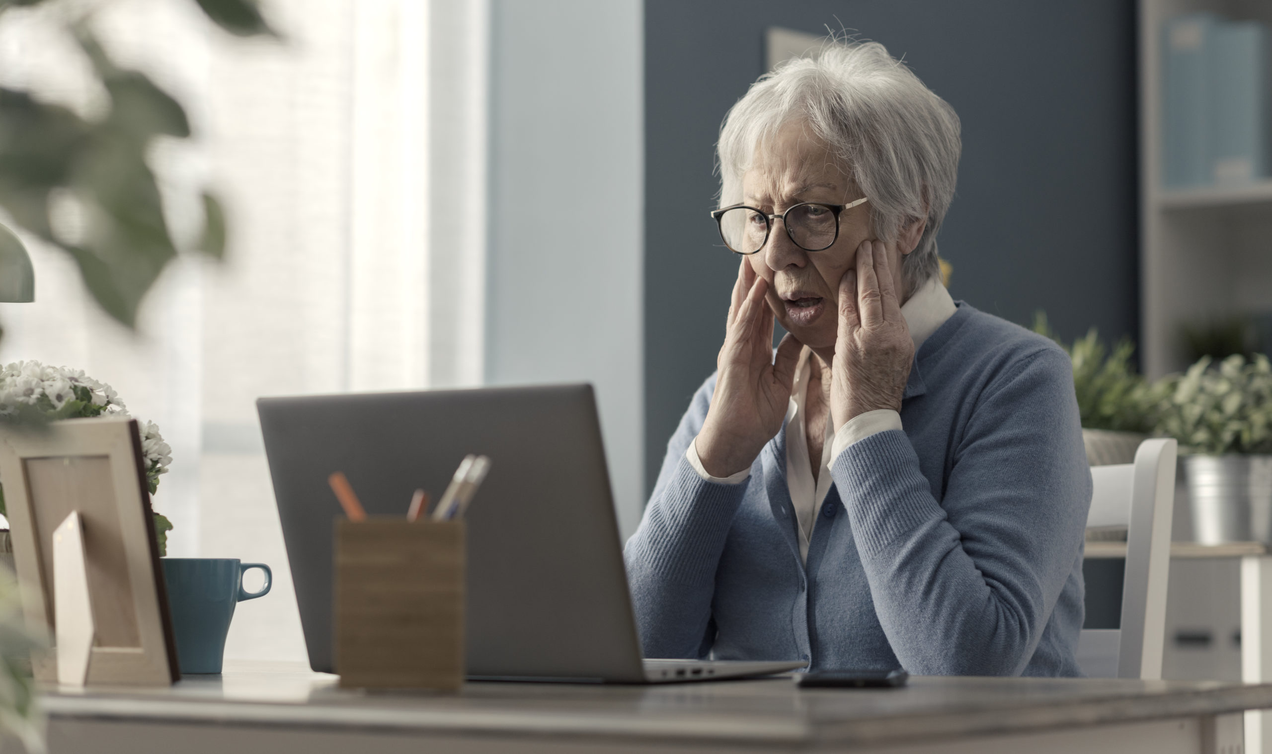 Senior woman struggling with technology, she is confused and staring at the computer screen