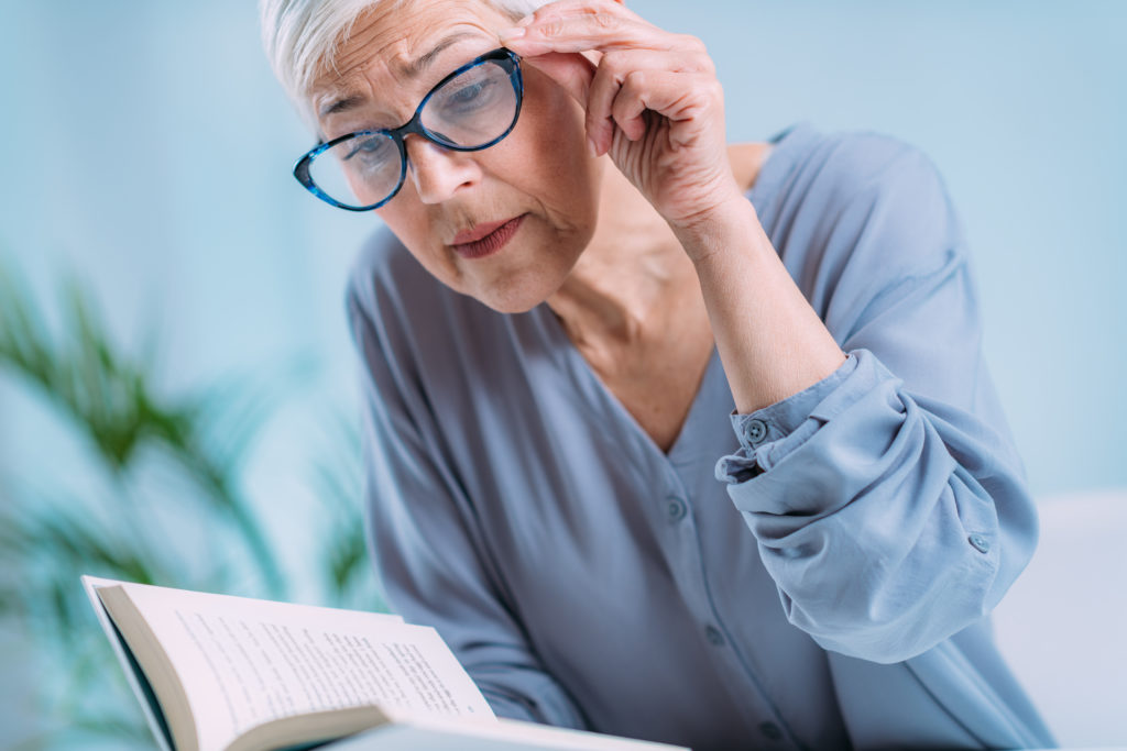 senior woman adjusting glasses while reading