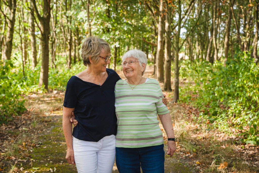 senior woman with dementia with her daughter walking embraced in a beautiful park