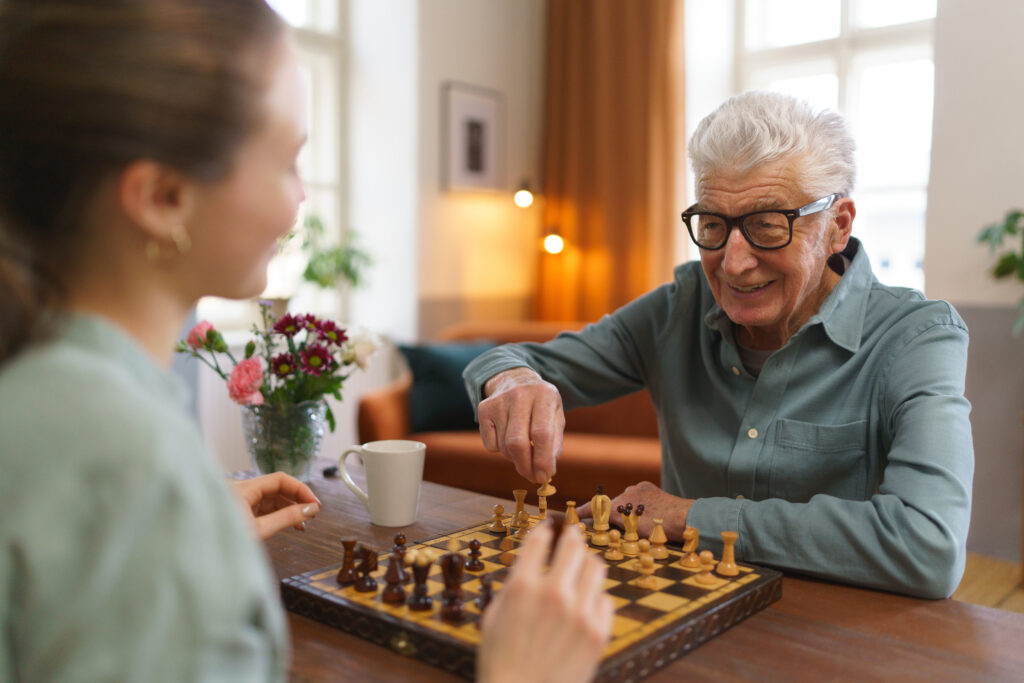 Senior man playing chess with his caregiver.