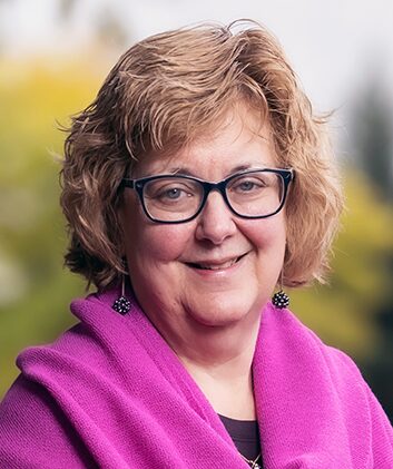 A woman in a pink sweater smiling.